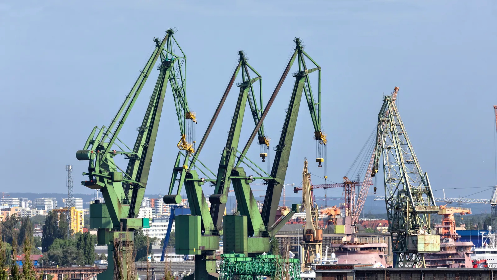 Portowe dźwigi nabrzeżne na tle zabudowy miasta i dalszych żurawi stoczniowych